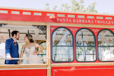 Newly weds staring at each other while riding a red Santa Barbara trolley.
