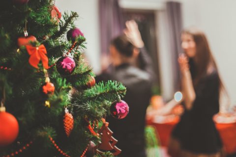 People enjoying a Christmas party in the background; close-up of a Christmas tree.
